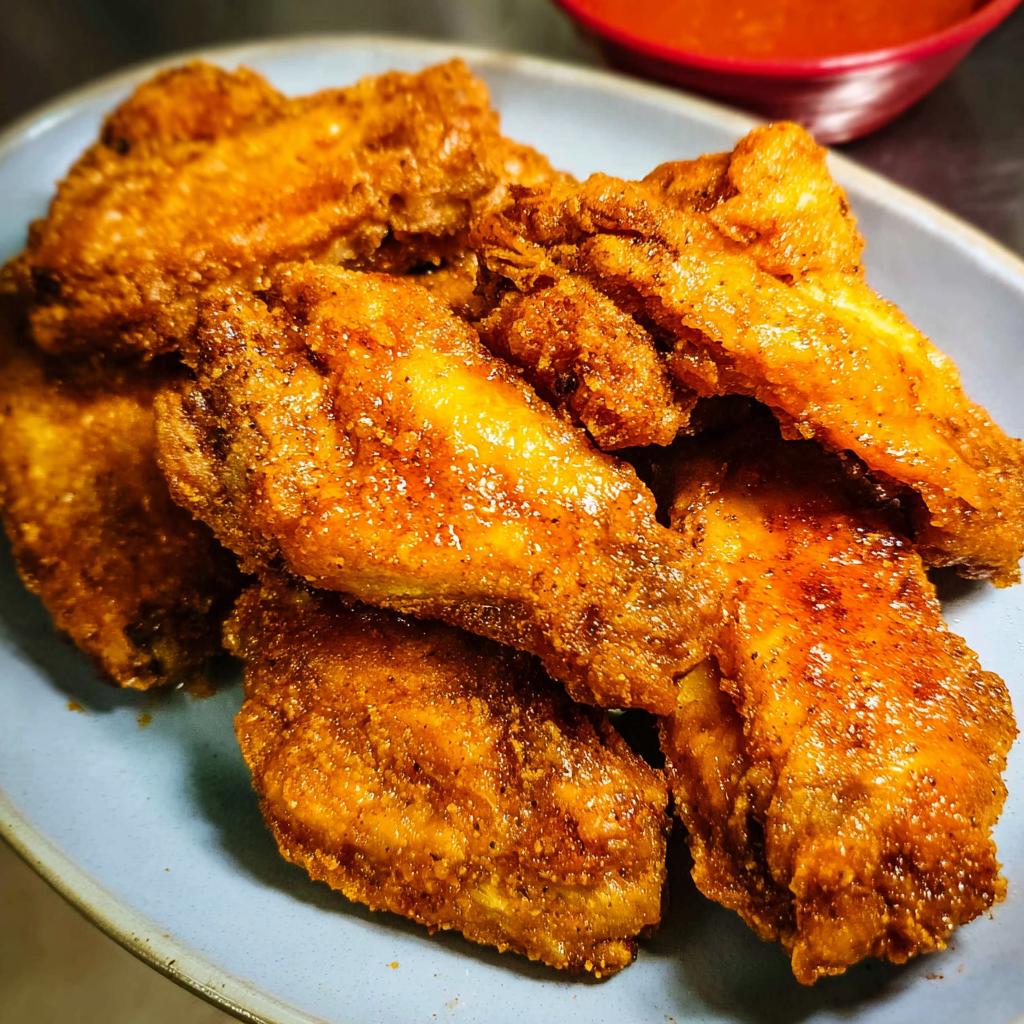 A close-up of golden brown, crispy chicken wings, seasoned and ready to be dipped in sauce.