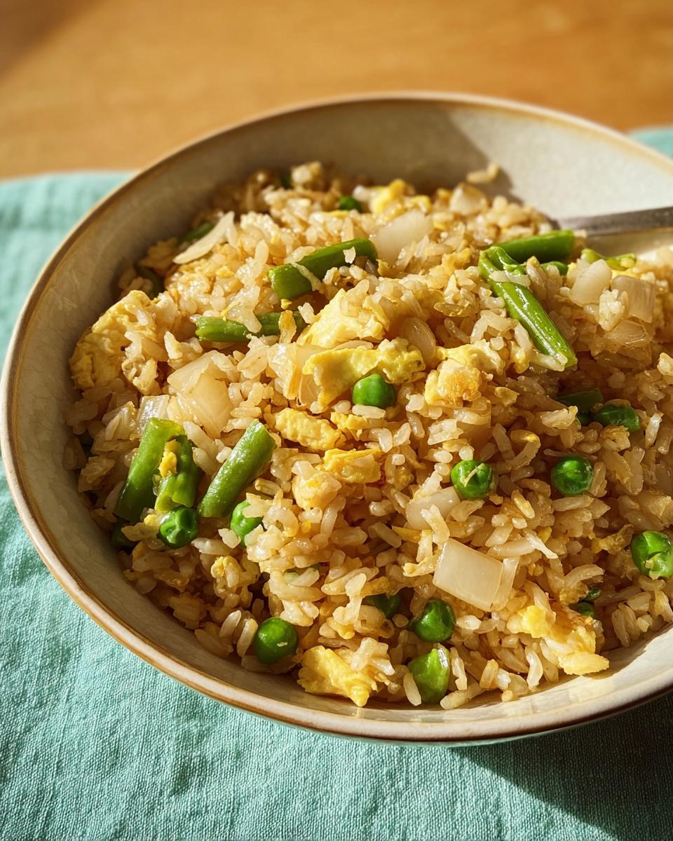 A close-up of a bowl of egg fried rice with peas, green beans, and scrambled egg pieces, part of 7-Ingredient Egg Recipes.