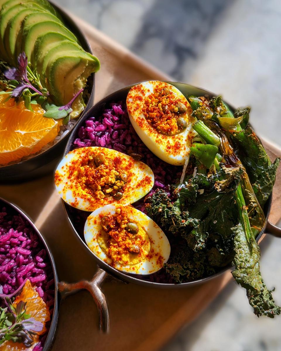 Close-up of a delicious egg recipe bowl with halved hard-boiled eggs, purple rice, avocado, and kale.