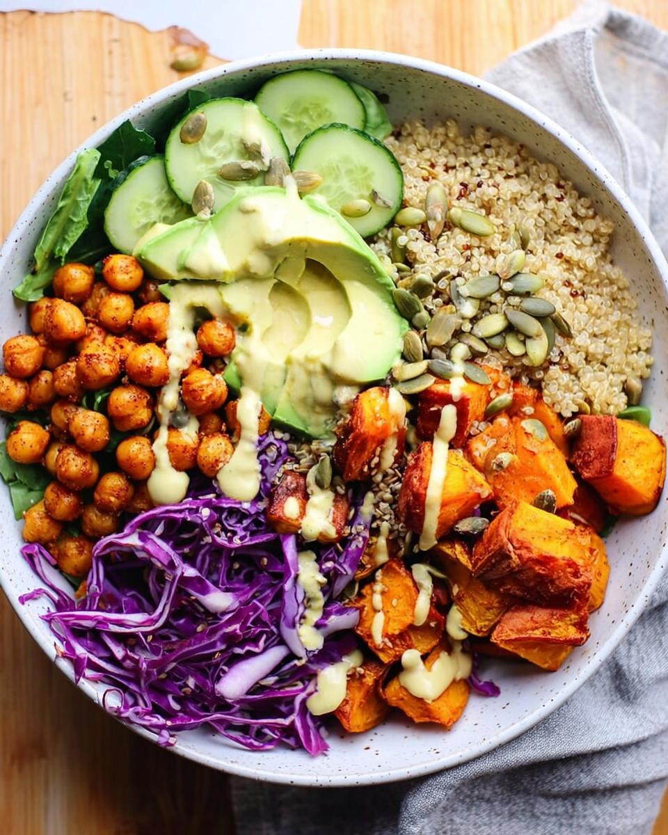 A vibrant and healthy rice bowl recipe featuring quinoa, roasted sweet potatoes, chickpeas, avocado, cucumber, and red cabbage with a creamy dressing.