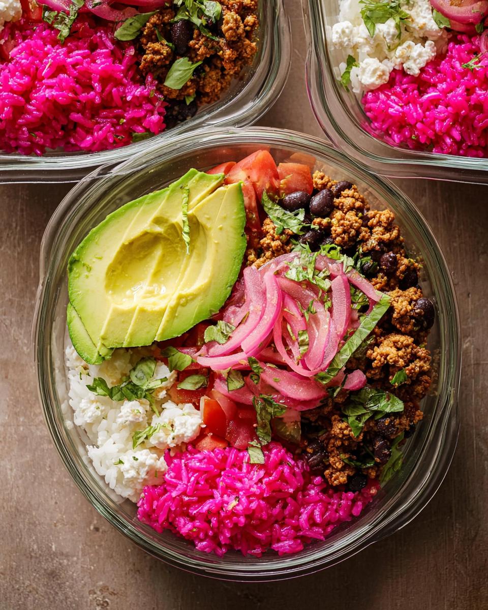 Overhead view of vibrant meal prep rice bowls with pink rice, avocado, ground meat, black beans, and pickled onions.