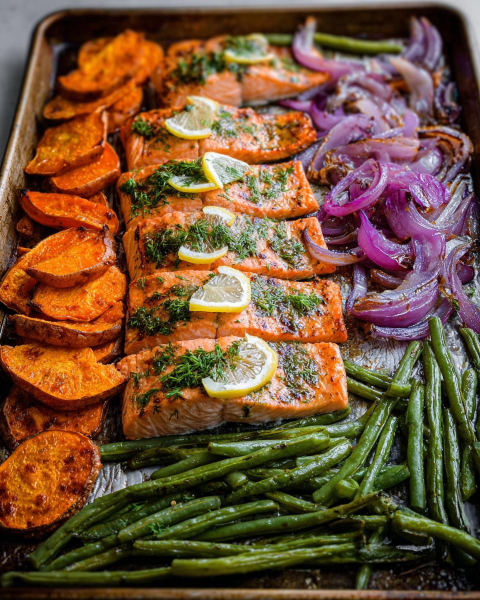 A full sheet pan of salmon recipes meal prep with roasted sweet potatoes, green beans, and red onions, garnished with lemon and dill.