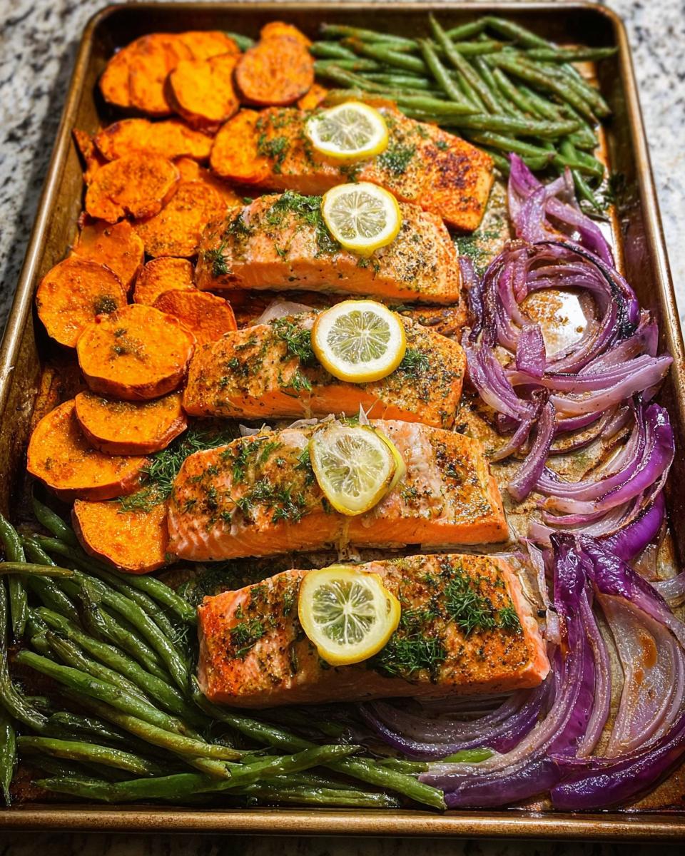Sheet pan with five salmon fillets, roasted sweet potato slices, green beans, and red onion wedges, perfect for salmon recipes meal prep.
