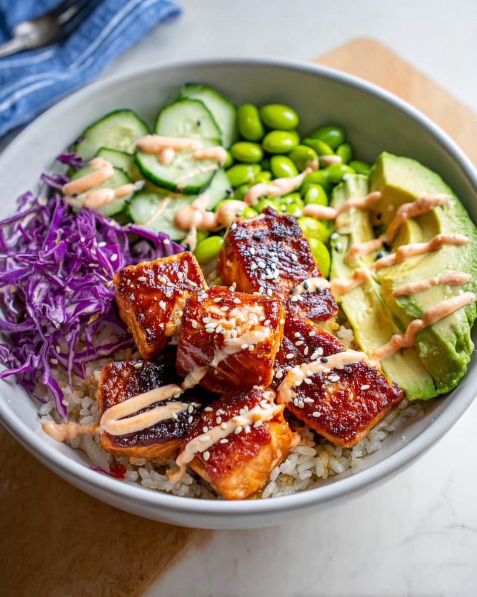 A delicious Crispy Salmon and Rice Bowl filled with glazed salmon, avocado, cucumber, edamame, and red cabbage.