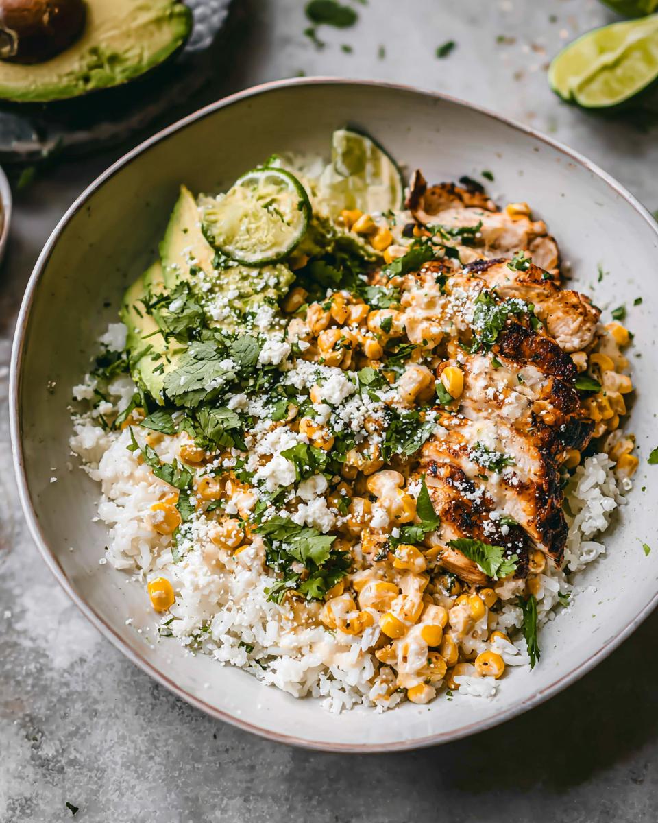 A vibrant Easy Street Corn Chicken Bowl filled with rice, grilled chicken, corn, avocado, cilantro, and lime wedges.