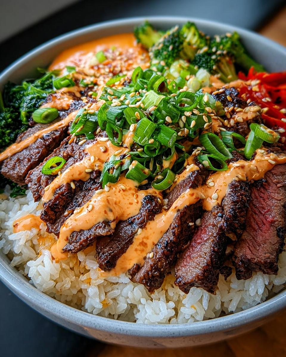 Close-up of Korean BBQ Steak Rice Bowls topped with spicy cream sauce, scallions, and sesame seeds.