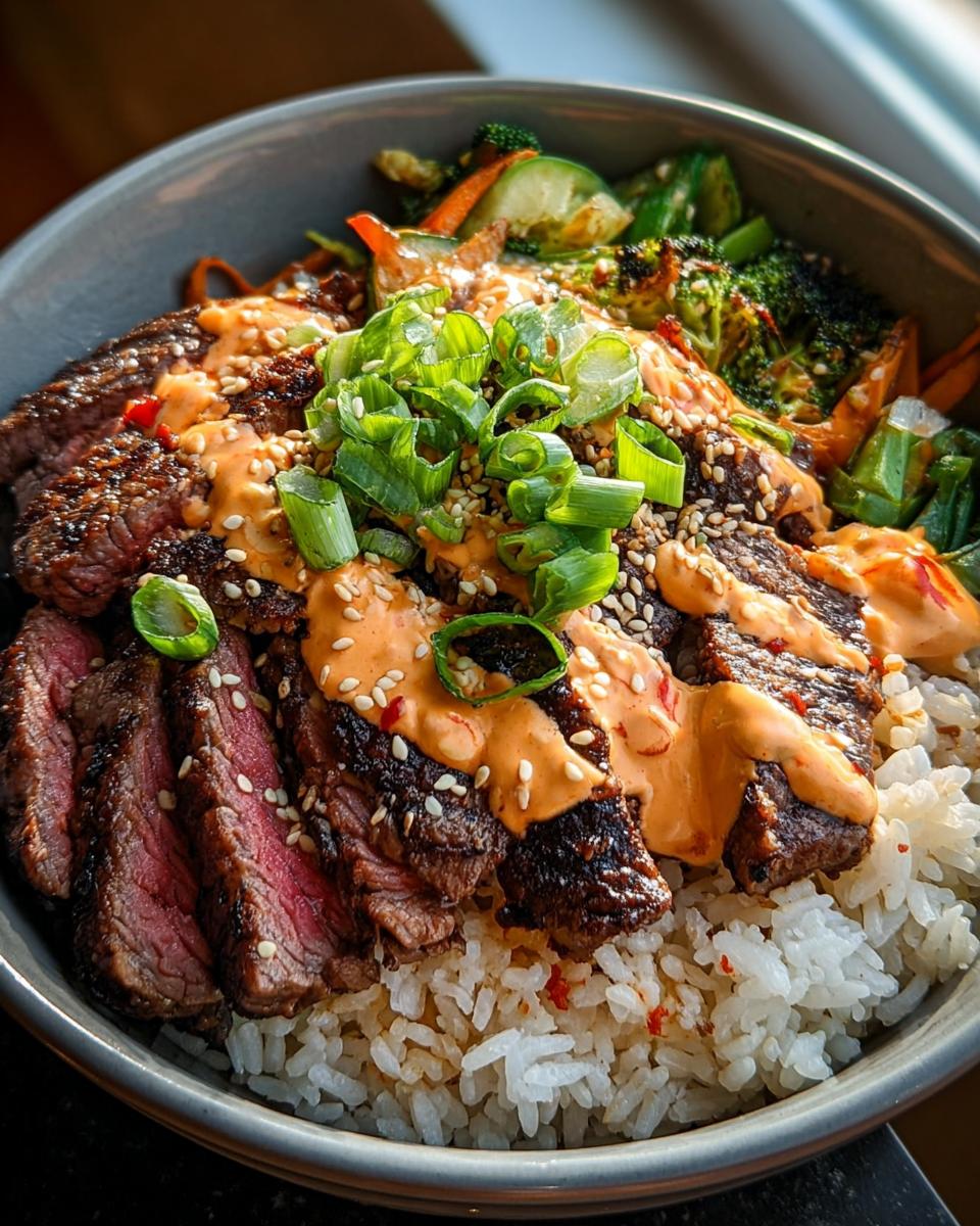 Close-up of Korean BBQ Steak Rice Bowls topped with spicy cream sauce, sesame seeds, and green onions.