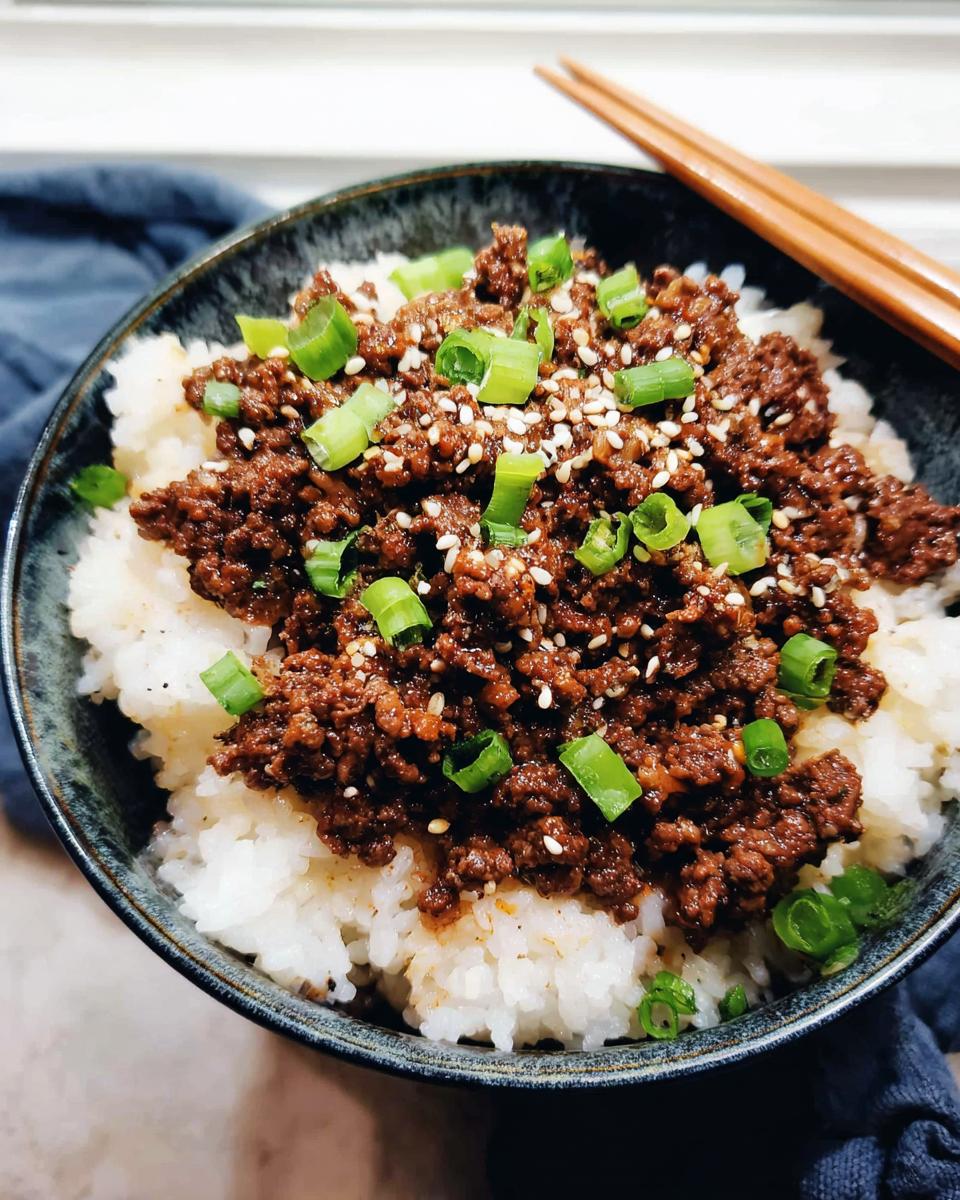 A close-up of a Korean Ground Beef Bowl, featuring seasoned ground beef over white rice, topped with sesame seeds and chopped green onions.