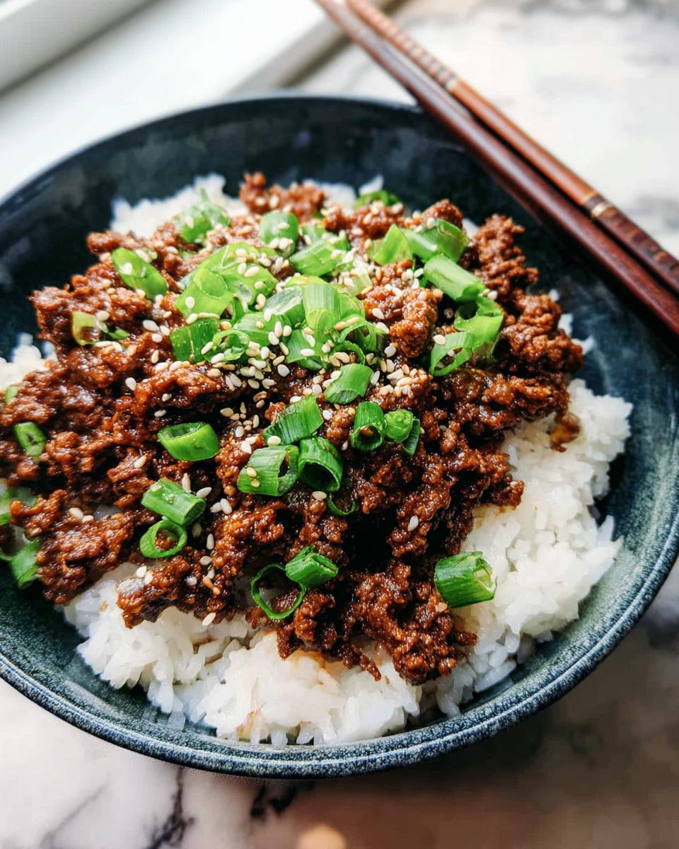 A close-up of a Korean Ground Beef Bowl, featuring savory ground beef over fluffy white rice, topped with green onions and sesame seeds.