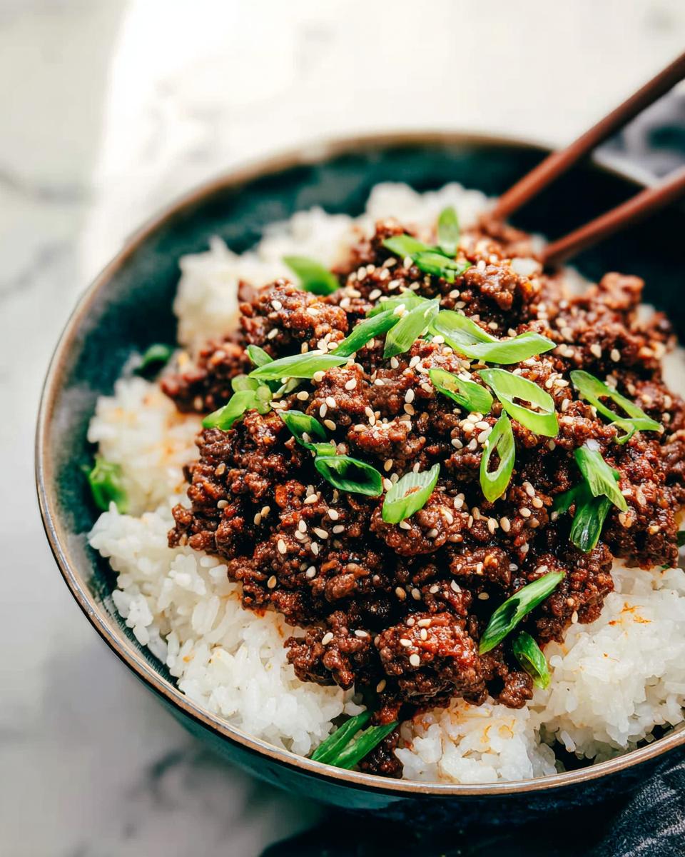 A close-up of a Korean Ground Beef Bowl, featuring seasoned ground beef over white rice, garnished with sesame seeds and chopped green onions.