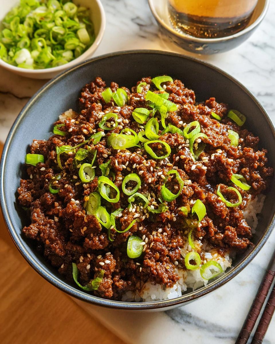 A close-up of a Korean Ground Beef Bowl served over white rice, topped with chopped green onions and sesame seeds.