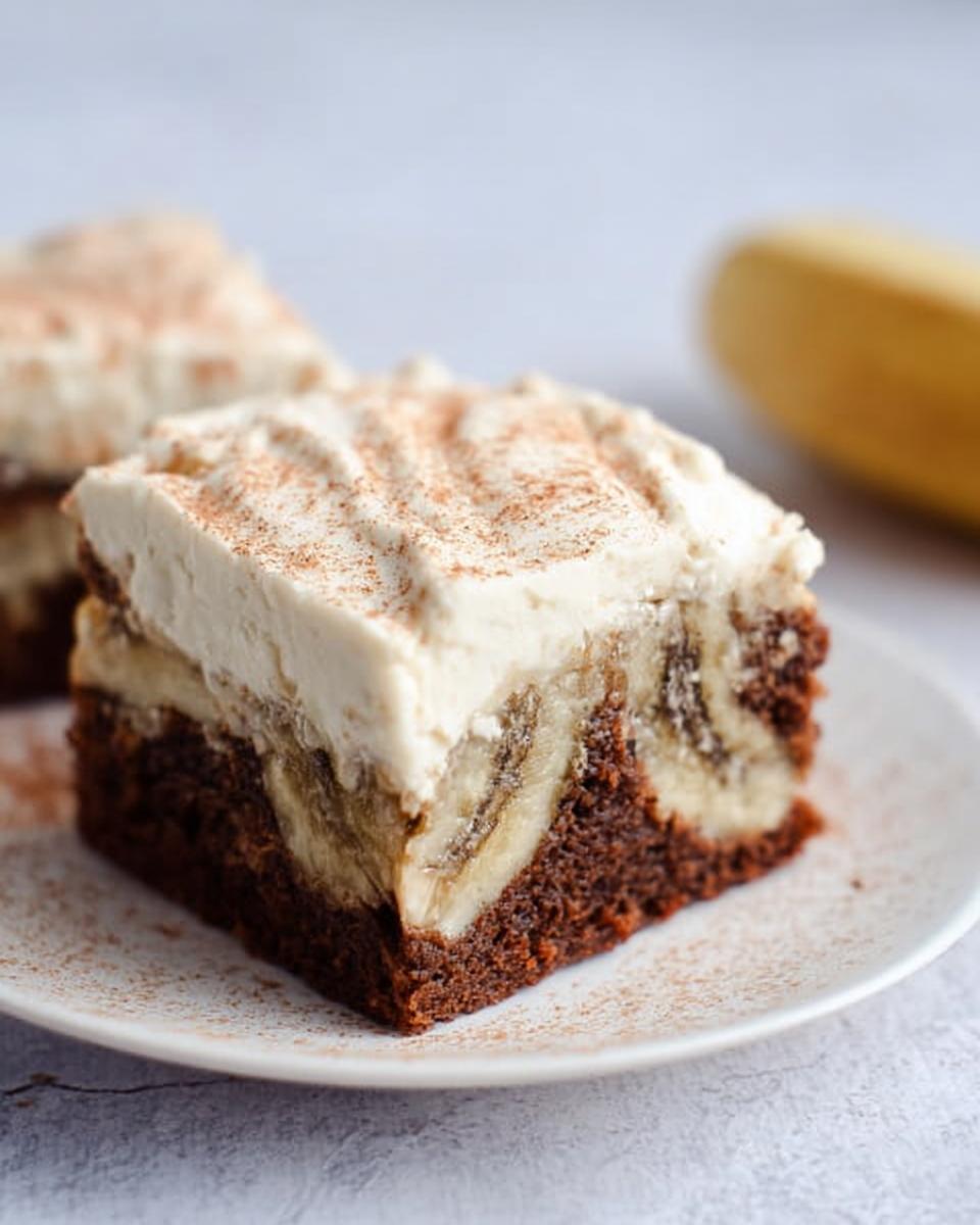 A close-up of a slice of Banana Bread Brownies Made Easy, topped with cream cheese frosting and cinnamon.