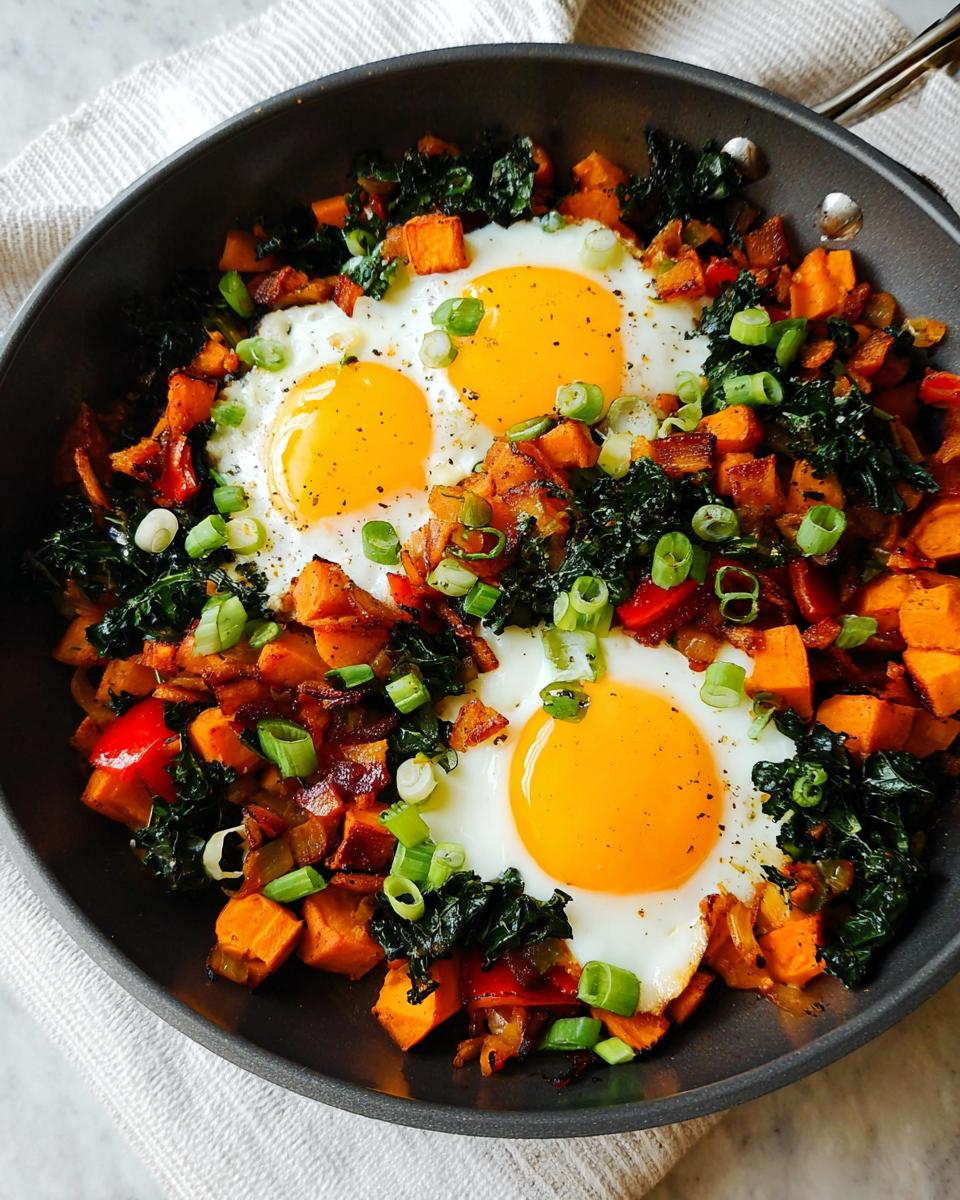 A hearty BREAKFAST SWEET POTATO hash served in a pan with three fried eggs and chopped green onions.