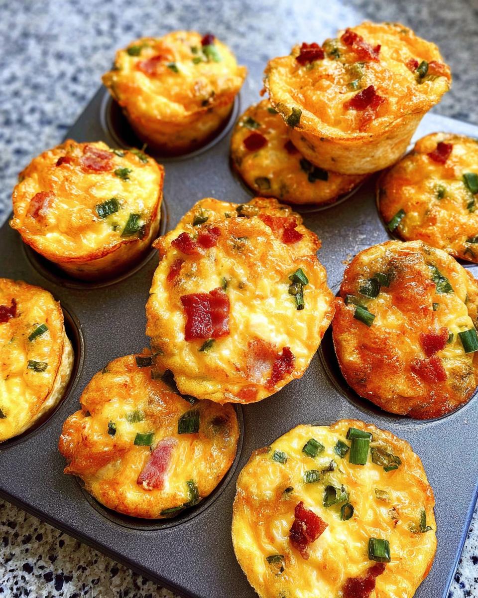 A close-up of golden brown Cheesy Muffin Tin Cottage Cheese Egg Bites with bacon and green onions in a muffin tin.