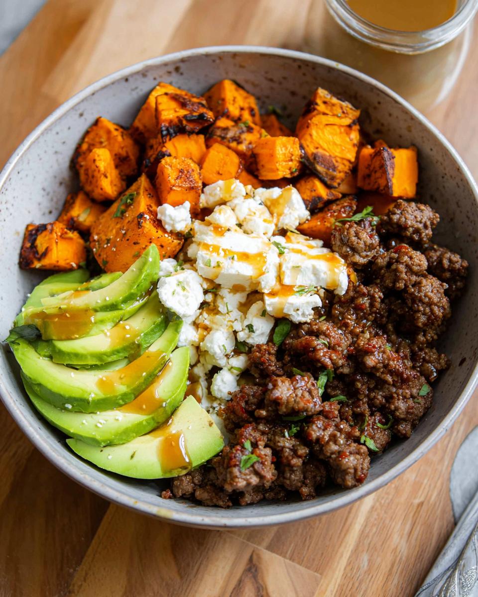 A delicious Ground Beef Hot Honey Bowl featuring seasoned ground beef, roasted sweet potatoes, sliced avocado, and crumbled feta cheese.