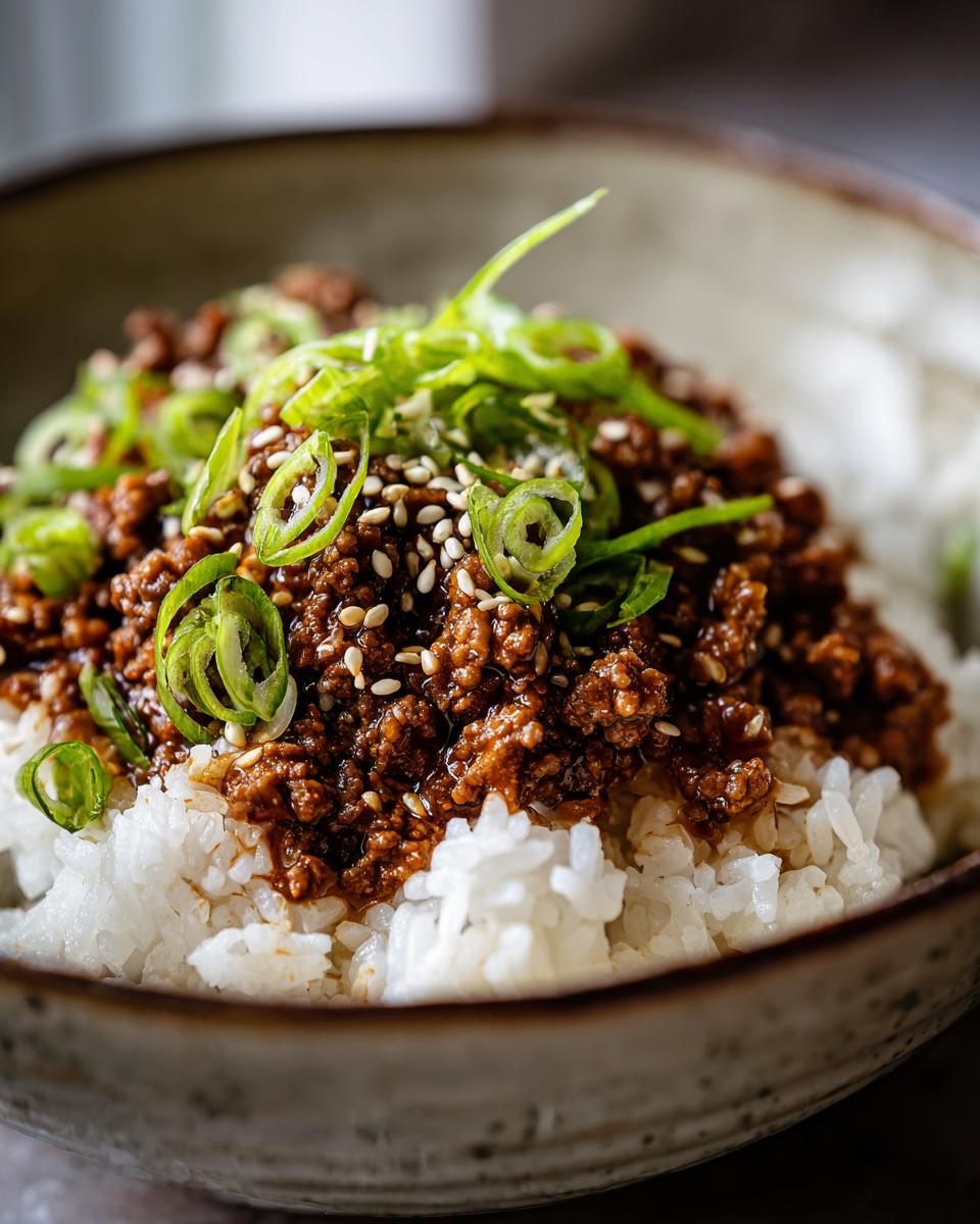Close-up of a Korean Ground Beef Bowl served over white rice, topped with sesame seeds and chopped green onions.