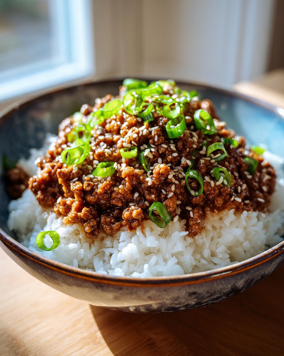 A close-up of a Korean Ground Beef Bowl, featuring savory ground beef over fluffy white rice, topped with green onions and sesame seeds.